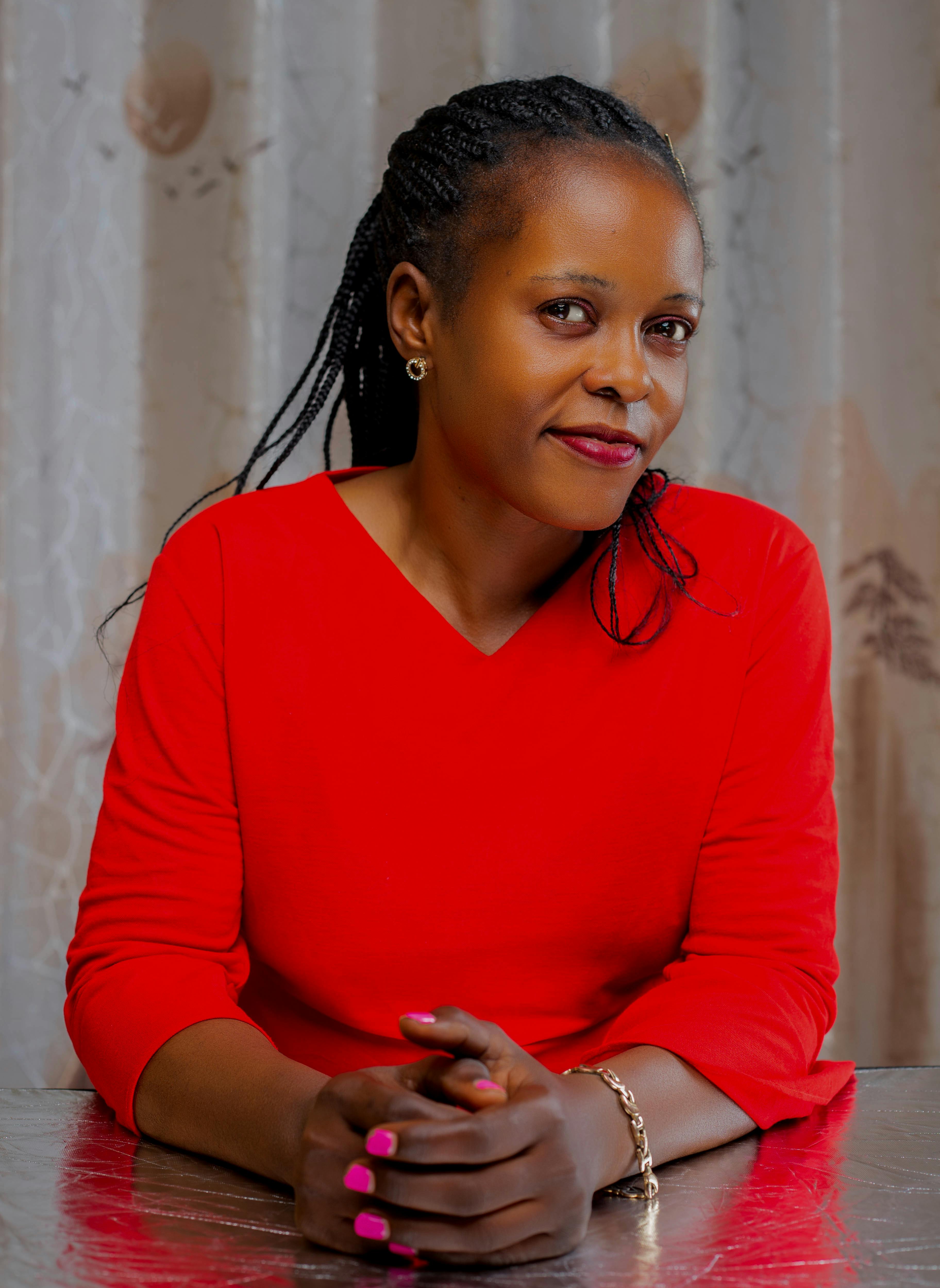 Close-up portrait of a smiling woman with braided hair in a red dress, ideal for lifestyle themes.