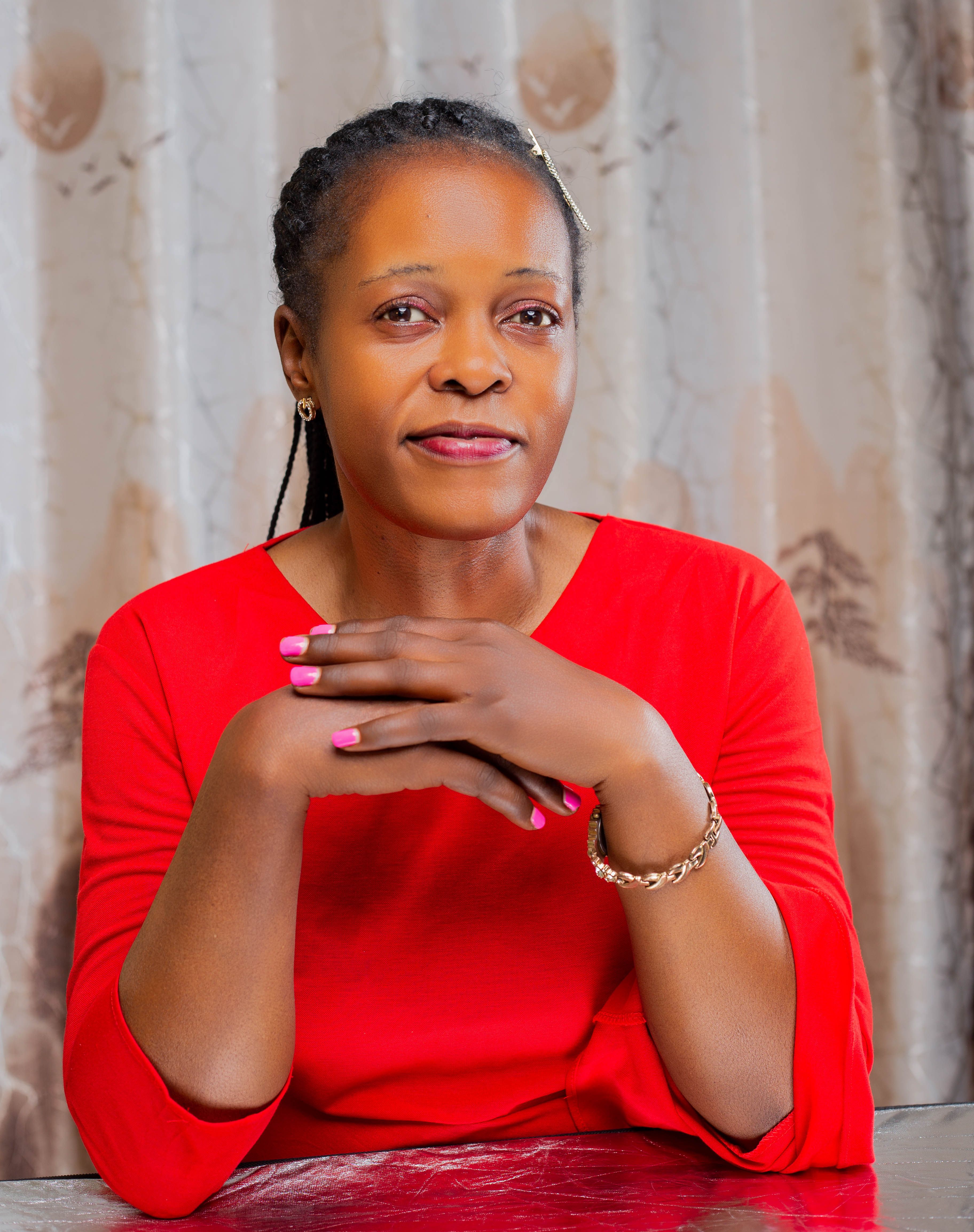 Portrait of a confident woman wearing a red blouse, seated indoors.