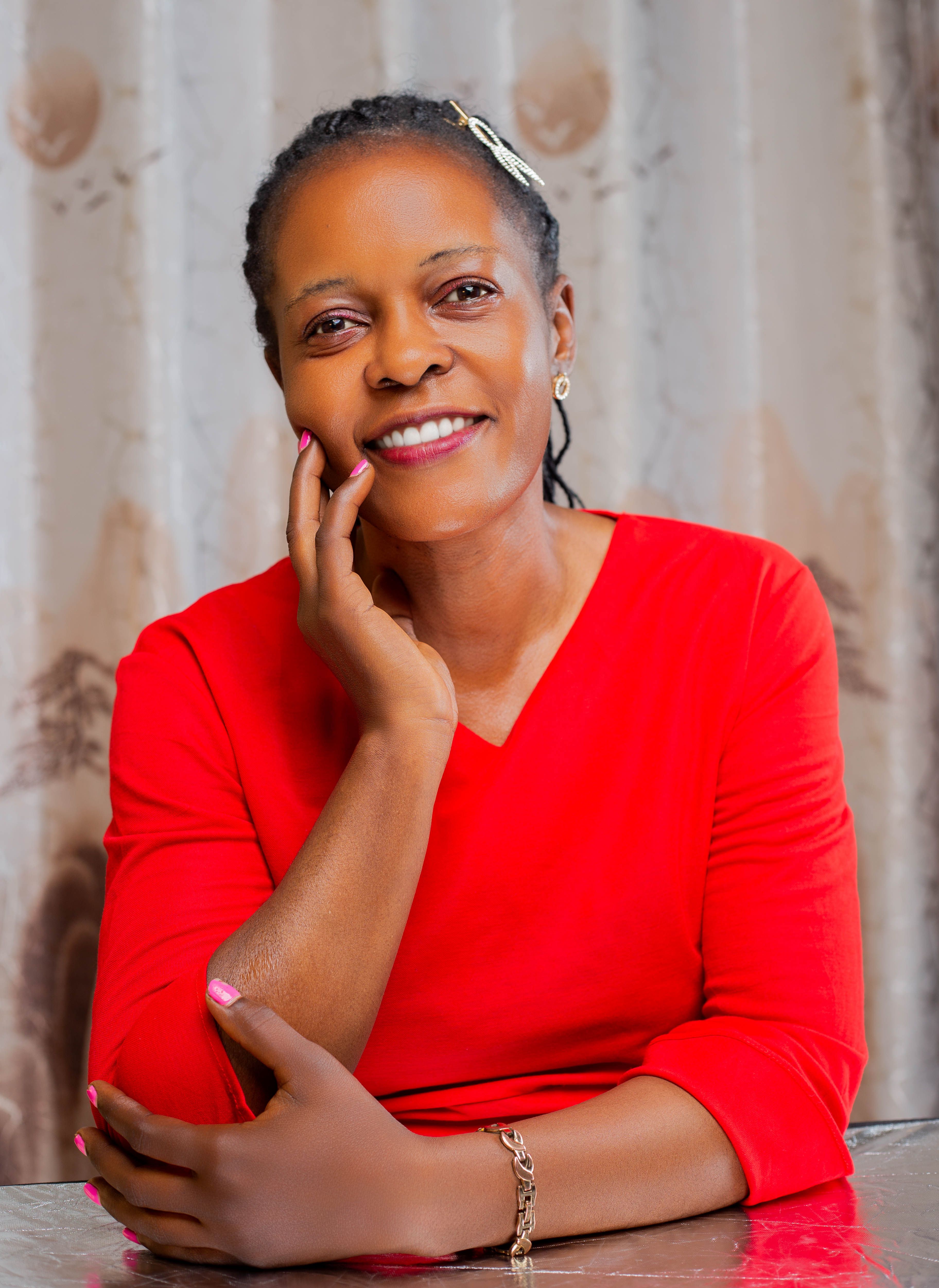 Portrait of a smiling woman in a red top seated indoors.