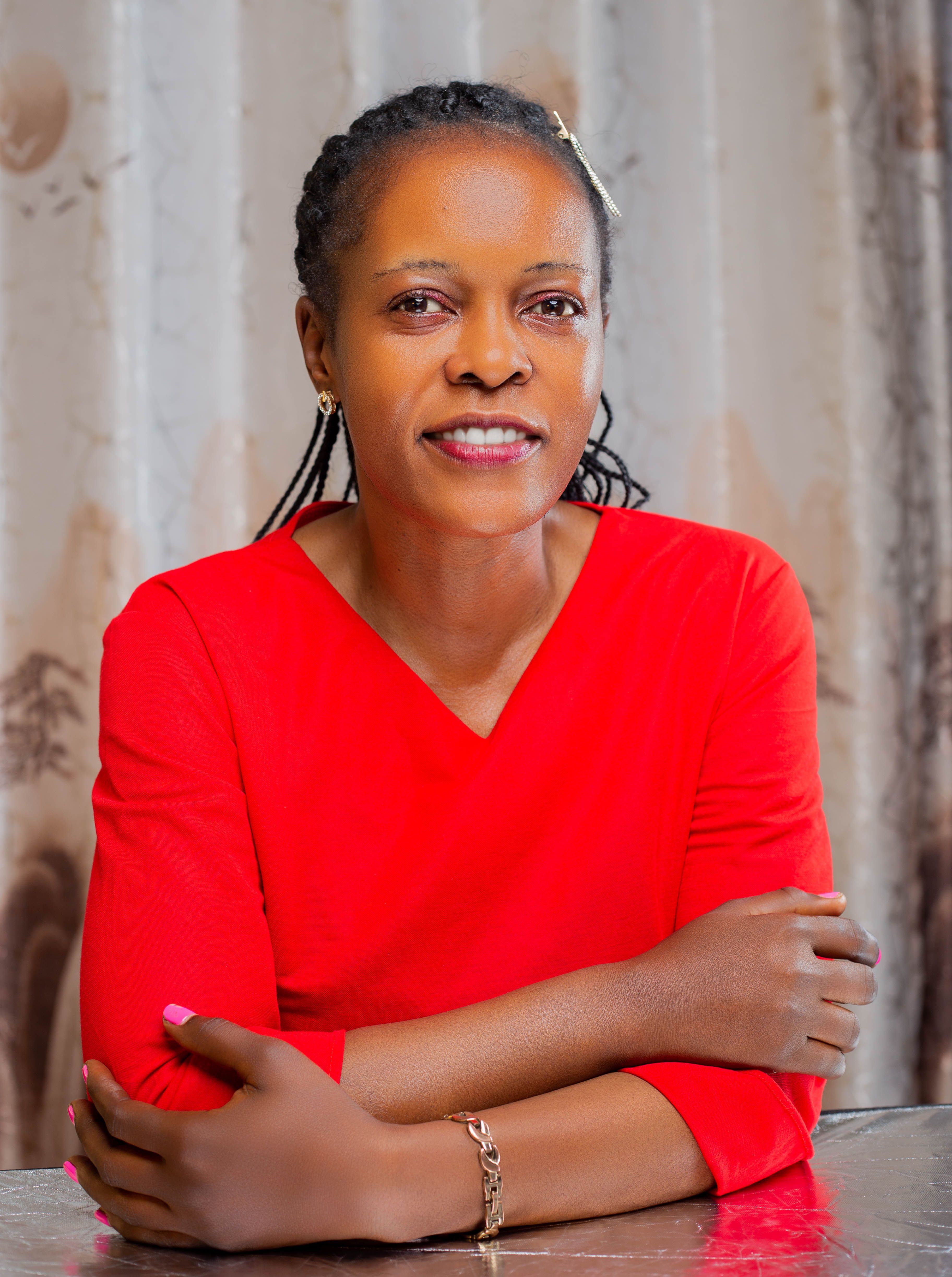 Portrait of a confident woman in a red top smiling indoors, showcasing elegance and poise.