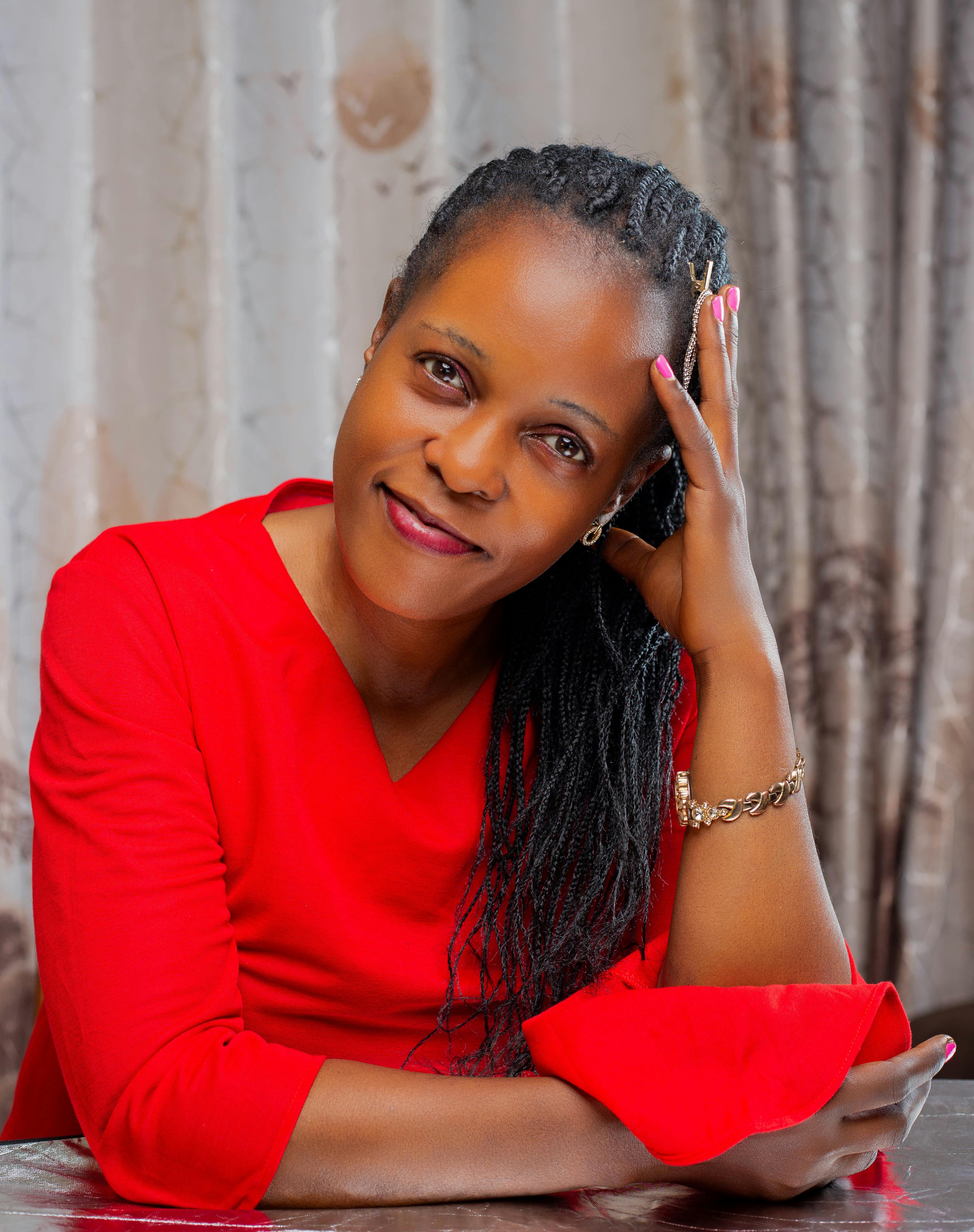 Portrait of a smiling woman in a red dress with braided hair, indoors.