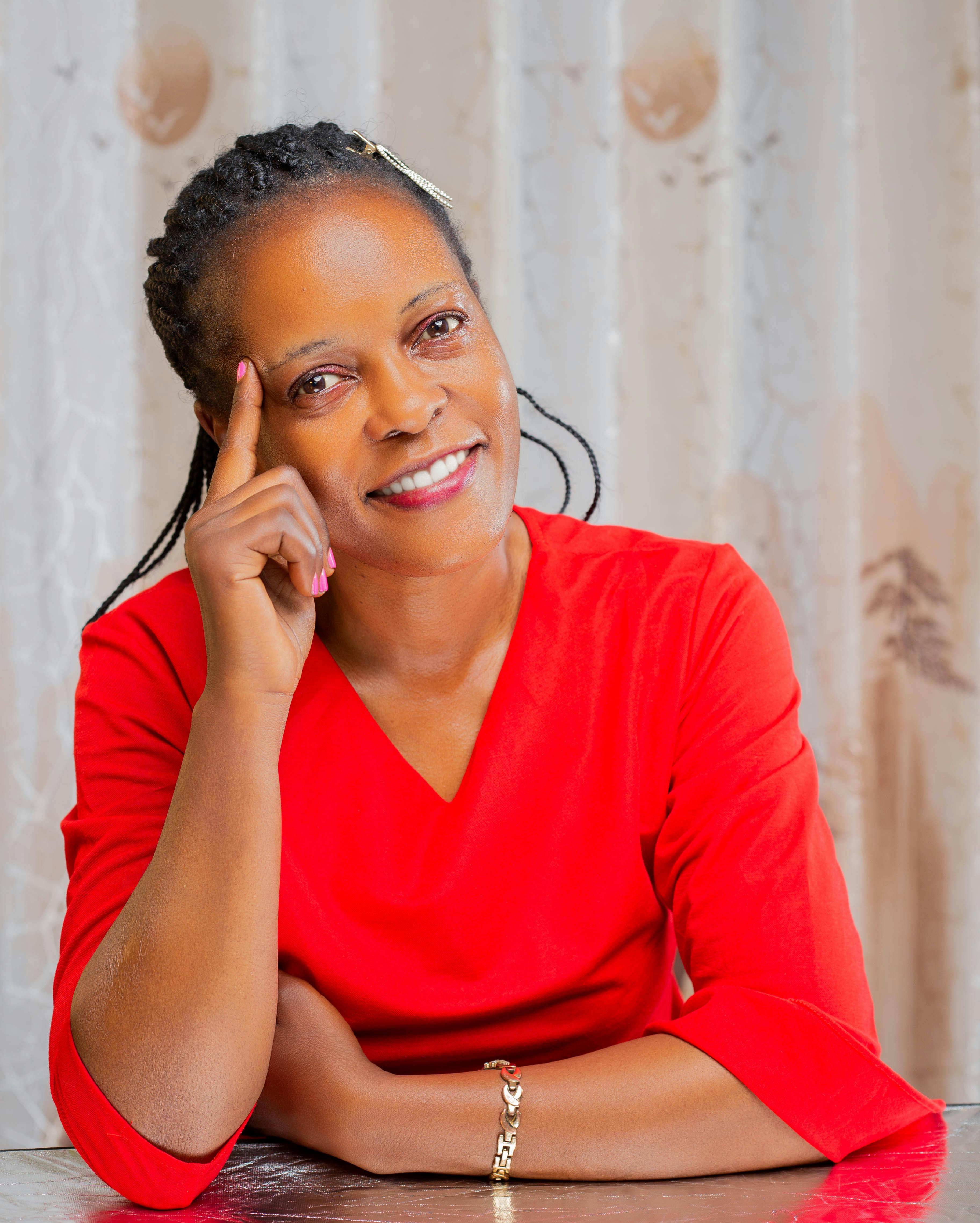 Portrait of an adult woman in a red top smiling indoors with a thoughtful expression.