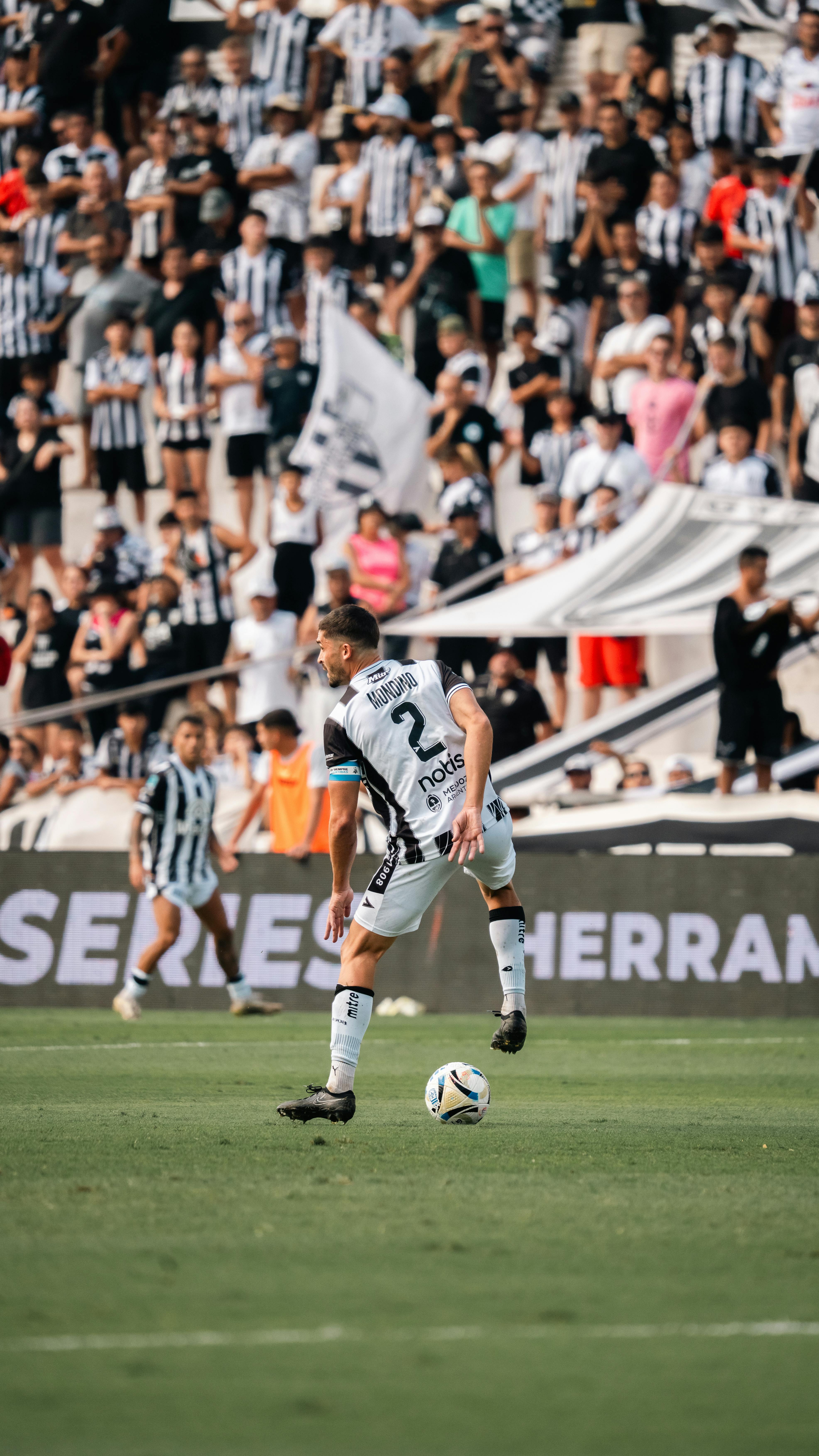 A dynamic soccer match captured with players in action and enthusiastic fans supporting in the stands.
