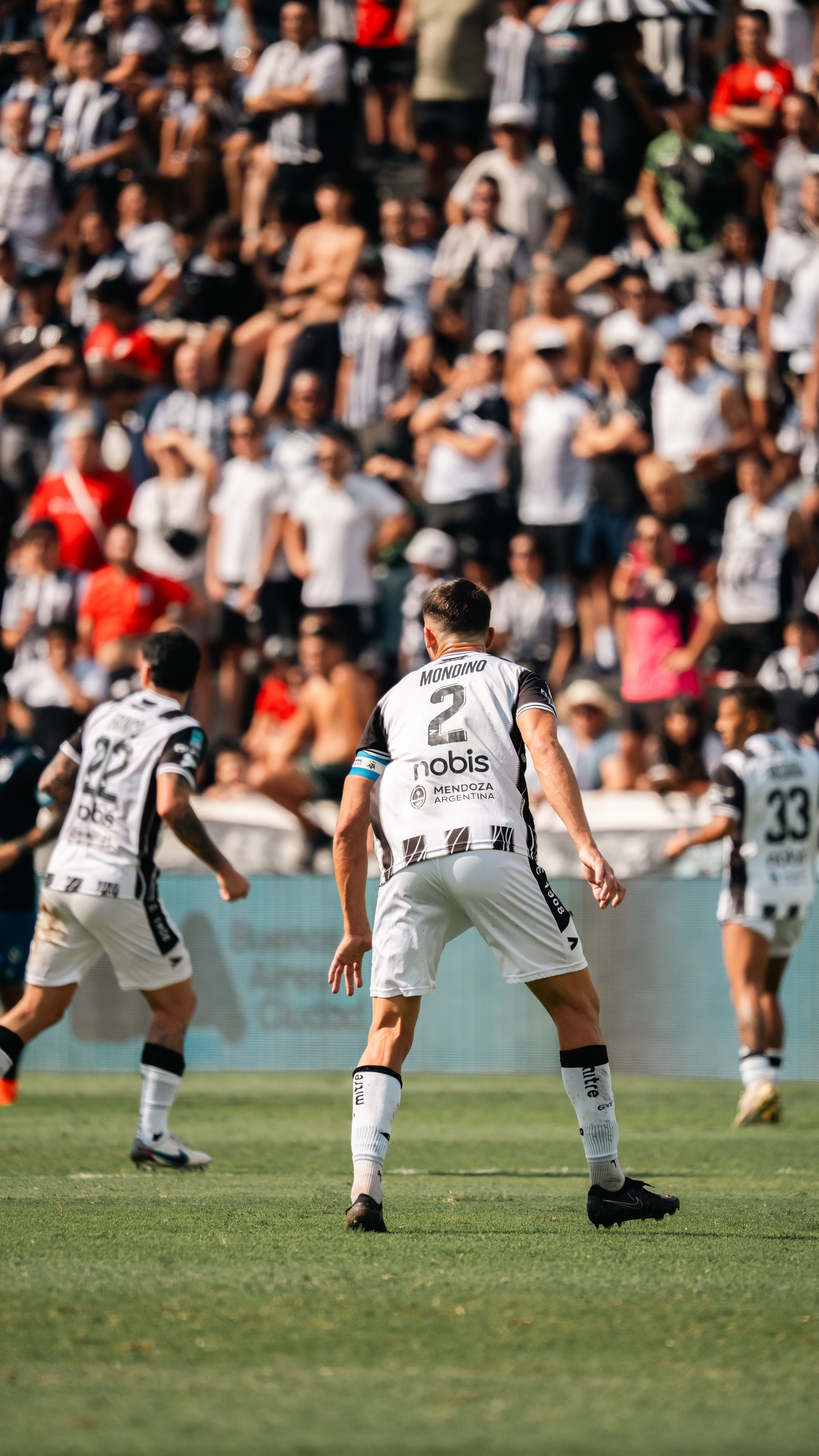 Intense soccer game with players and enthusiastic crowd in a stadium setting.