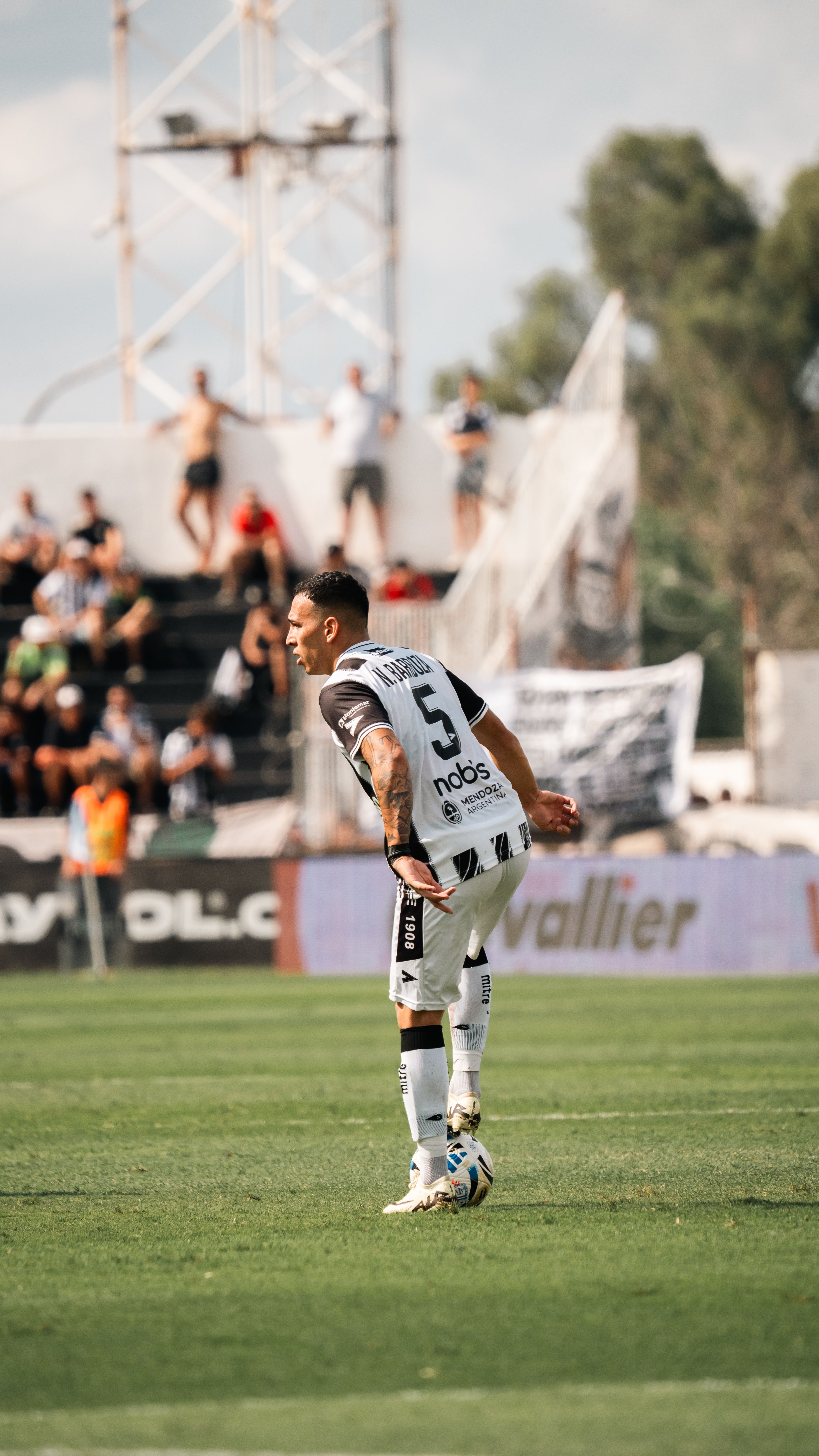 Soccer player preparing to kick in a lively outdoor match with an audience.