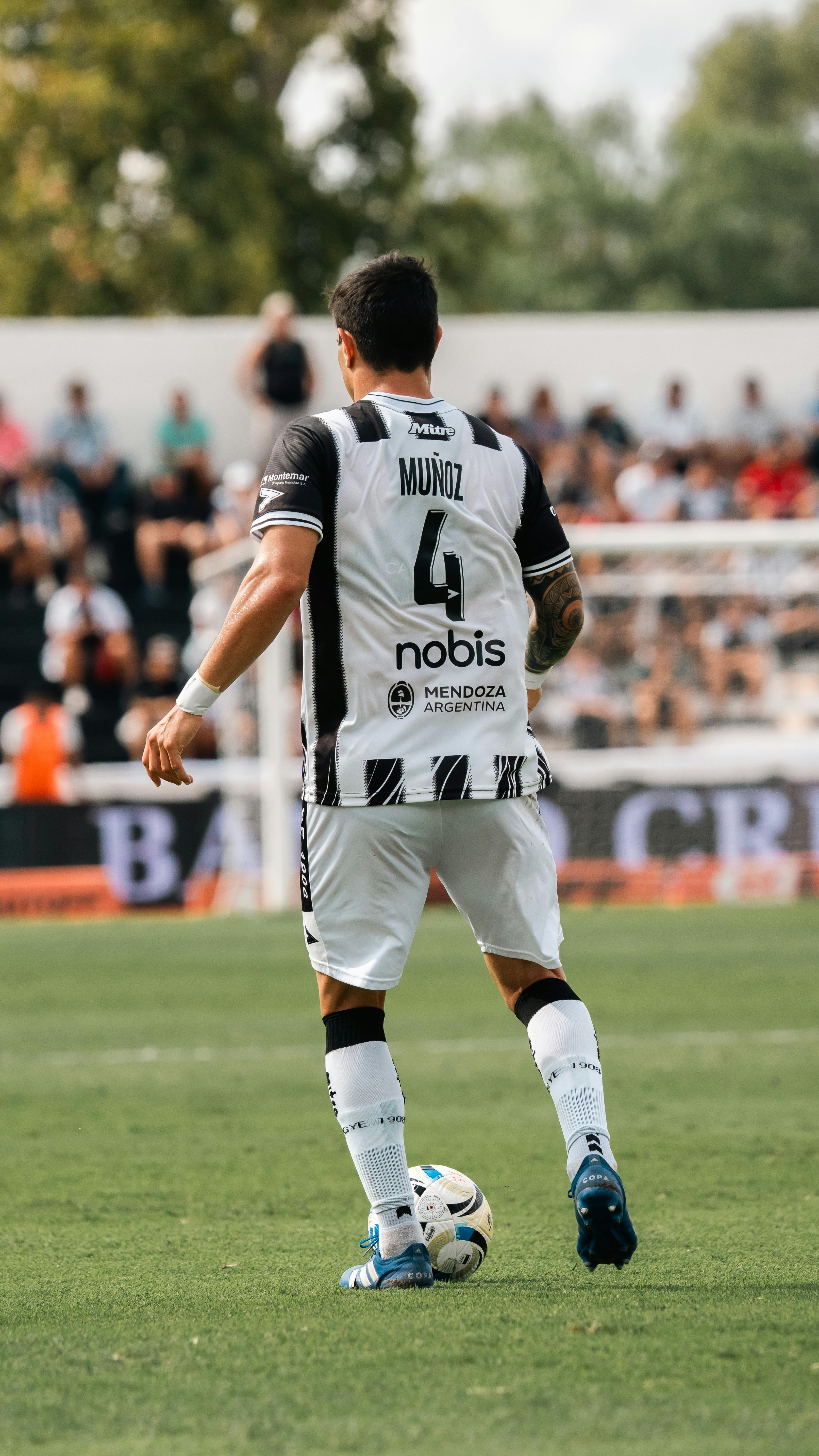 A soccer player in action on a grass field during a competitive match.