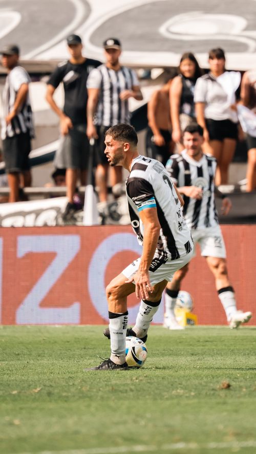 Free Athlete in black and white striped jersey dribbling during a soccer match in stadium. Stock Photo