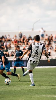 Action shot of a lively soccer match in a sunny outdoor stadium with players in motion.