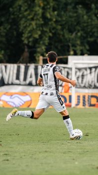 Athlete running on grassy field during daylight soccer match.