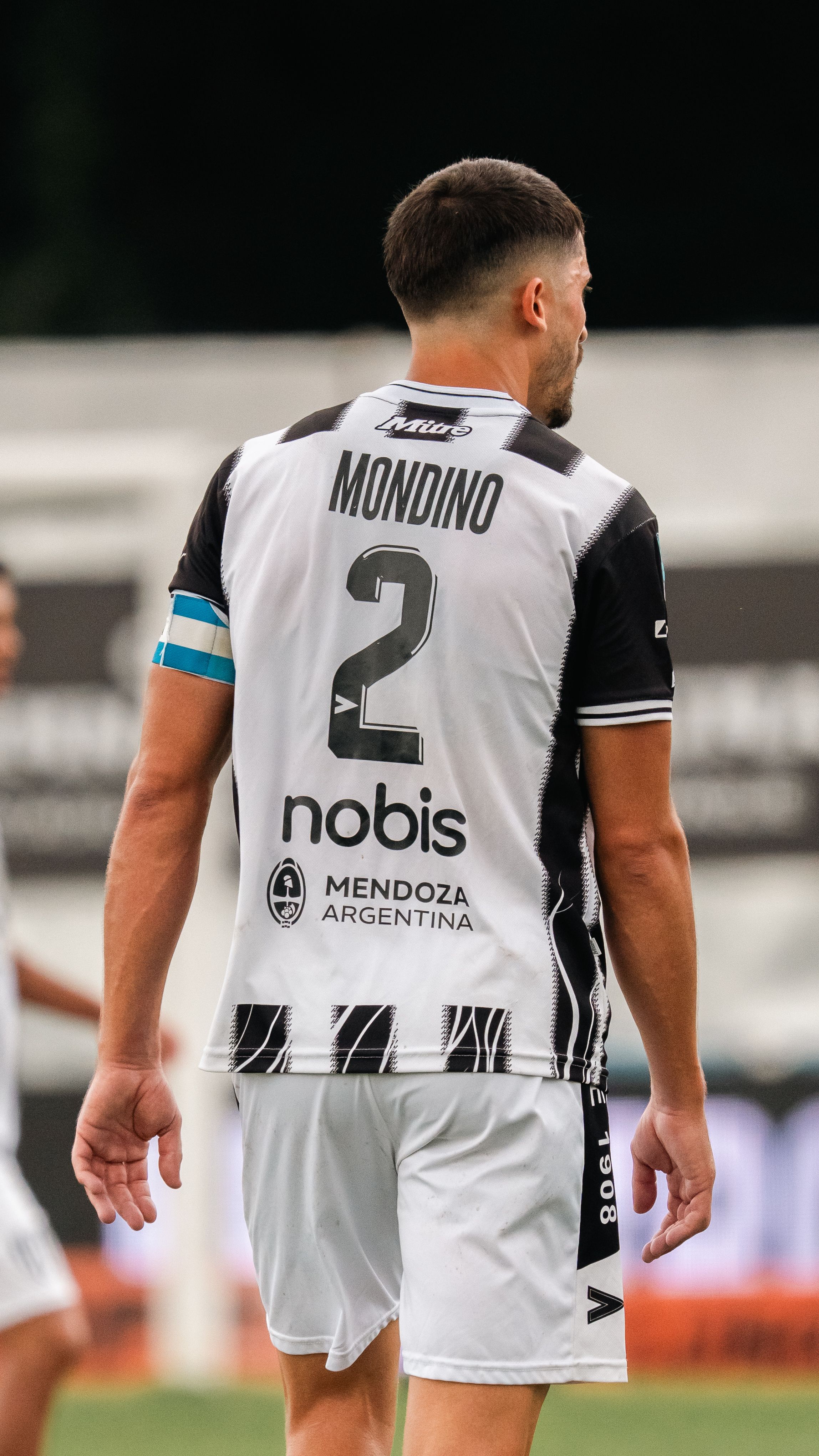 Back view of a soccer player on the field wearing a Mendoza team jersey.