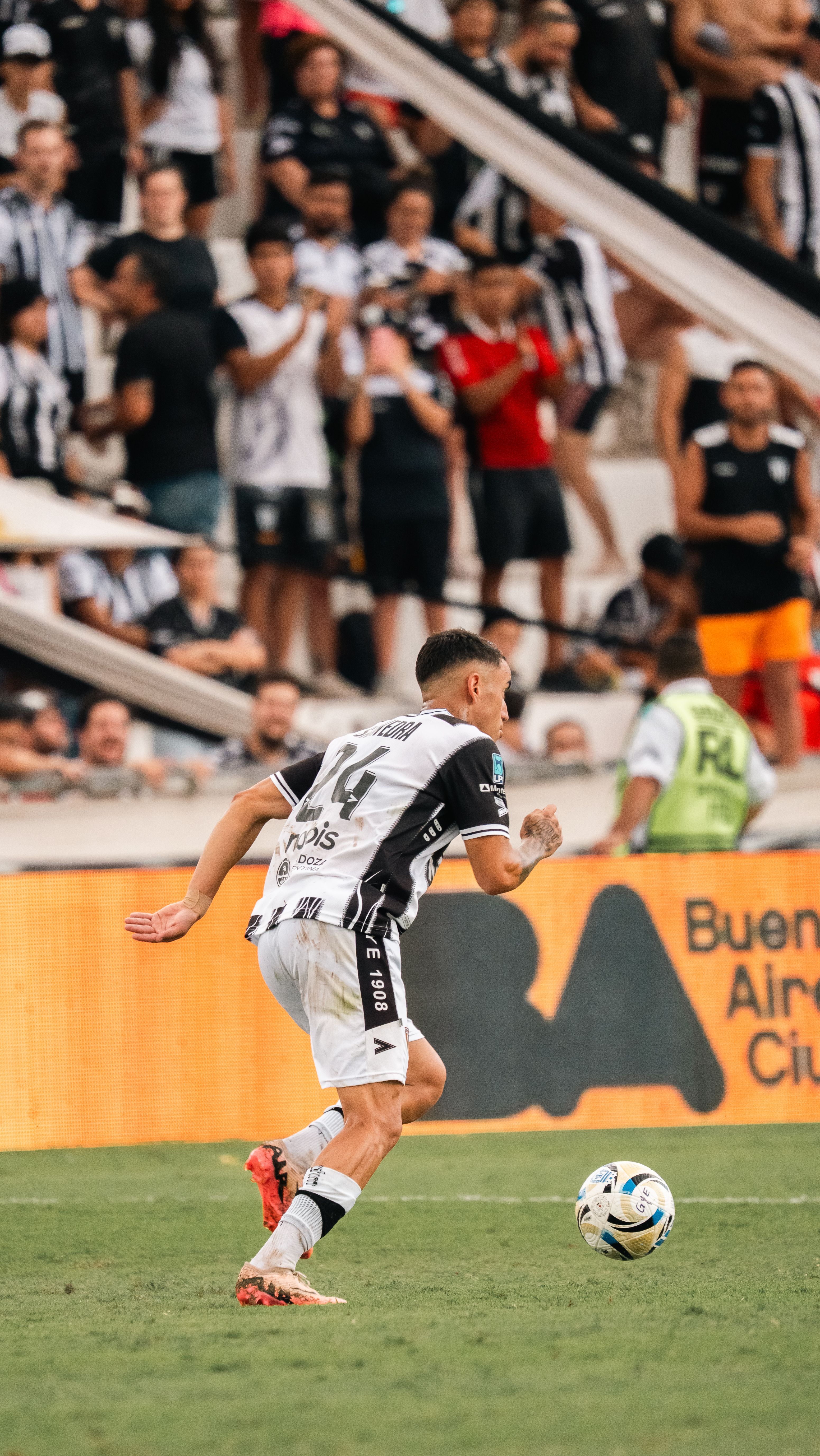 Soccer player mid-action with a vibrant crowd in the background, capturing game intensity.
