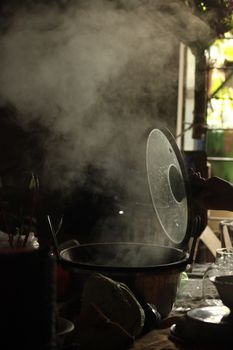 Steam rises from a cooking pot in a warmly lit kitchen, offering a cozy ambiance.