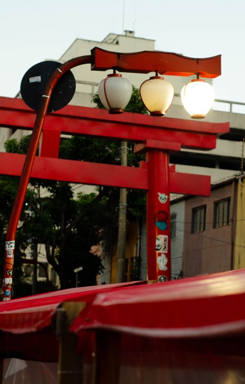 Free A red Torii gate and lanterns in a bustling urban environment at dusk. Stock Photo