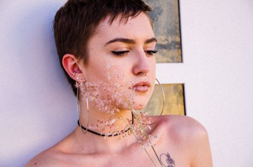 Free A close-up portrait of a woman with short hair and a flower, showcasing an artistic style with warm lighting. Stock Photo
