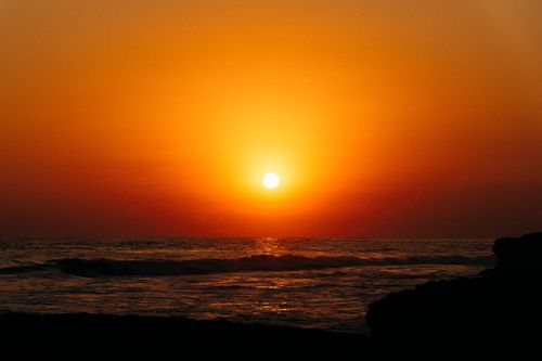 Free Beautiful sunset over the ocean with vibrant orange skies and gentle waves. Stock Photo