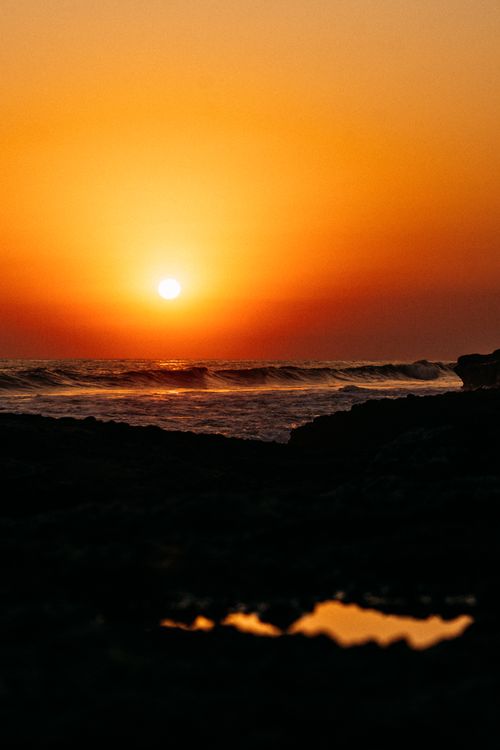Free Captivating sunset over the ocean with bright orange hues casting a warm glow on the waves. Stock Photo