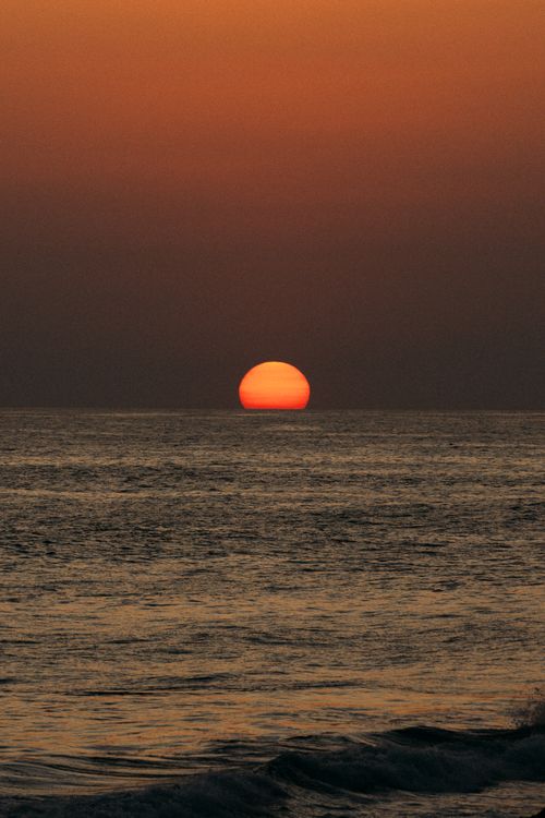 Free Capture the stunning beauty of an ocean sunset with vibrant orange hues in the horizon. Stock Photo