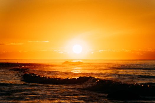 Breathtaking view of a golden sunset over the ocean with gentle waves, captured in stunning clarity.