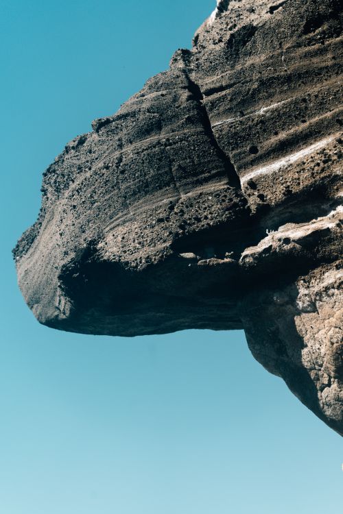 Free A striking rock formation with intricate textures set against a clear blue sky. Stock Photo