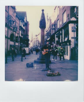 在繁华的历史城市广场，一位街头音乐家正在纪念碑附近弹吉他