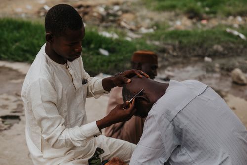 Free A barber cuts a man's hair outdoors, showcasing a traditional haircut method. Stock Photo