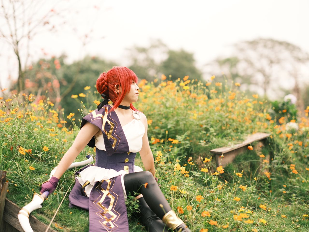 a cosplayer dressed in a costume sits serenely in a field of vibrant f