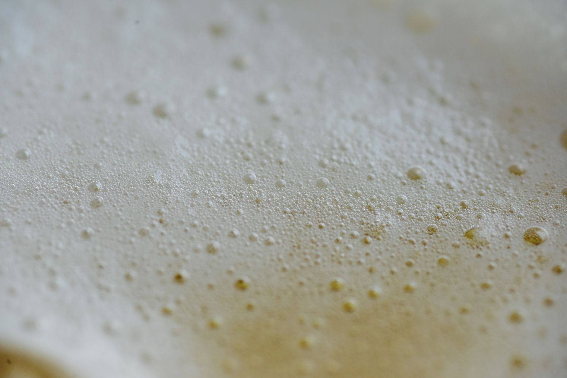 Detailed macro shot capturing the effervescence and texture of bubbles on a light beige surface.