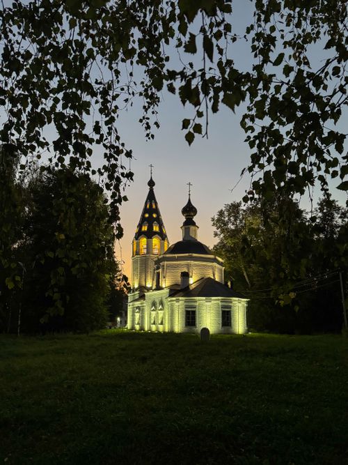 Free A beautifully lit church at twilight, surrounded by trees and twilight hues, creating a serene atmosphere. Stock Photo