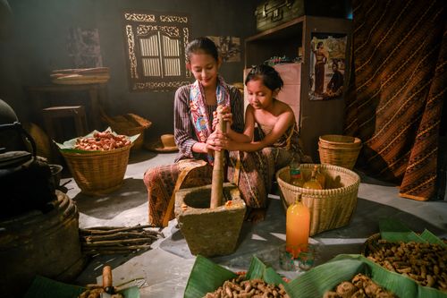 Free Two women prepare traditional Jamu in a rustic Indonesian kitchen using natural ingredients. Stock Photo