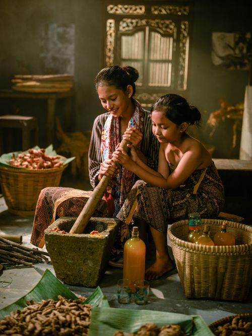 Free Mother and child preparing Jamu in a rural Indonesian kitchen using traditional methods. Stock Photo