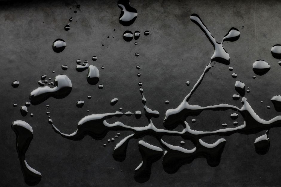Artistic display of water drops on a textured dark background.