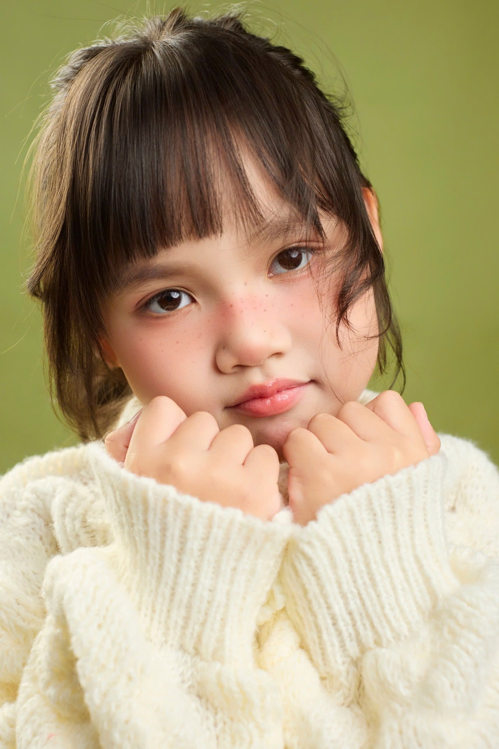 Close-up portrait of a young girl in a cozy sweater, pensive and thoughtful expression.