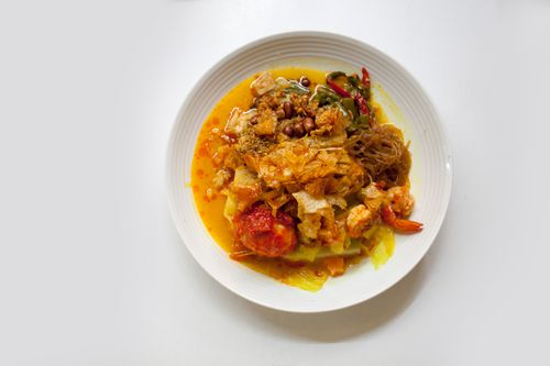 Free A vibrant and colorful spicy curry noodle dish topped with shrimp and vegetables, served on a white plate. Stock Photo