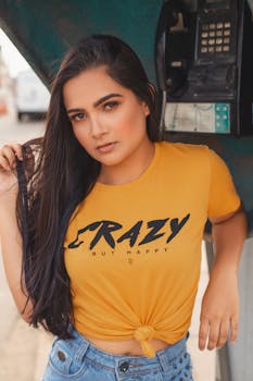 一位自信的年轻长发女子在户外电话亭旁随意摆着姿势