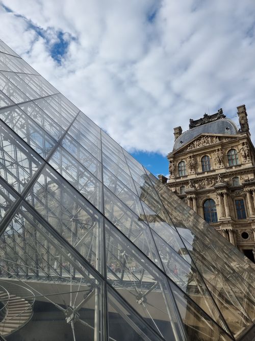 Free The iconic Louvre Pyramid contrasts with the historic Louvre Museum in Paris. Stock Photo