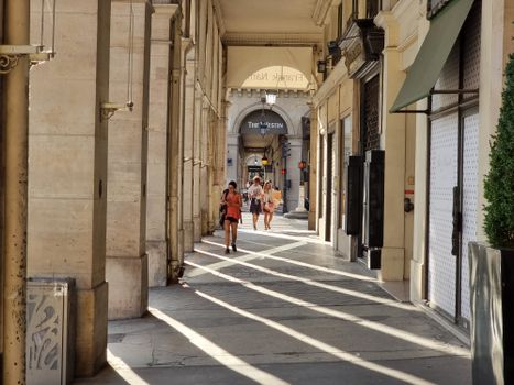 Sunlit passageway in Paris with people walking. Summer day, The Westin Paris Vendôme hotel.