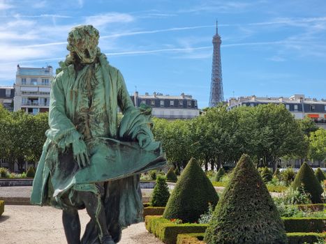 Elegant statue in Paris garden with Eiffel Tower in the background on a sunny day.