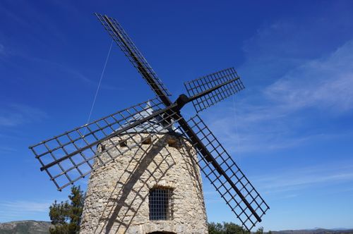 Free A beautifully preserved stone windmill stands under a vibrant blue sky, capturing rural charm. Stock Photo