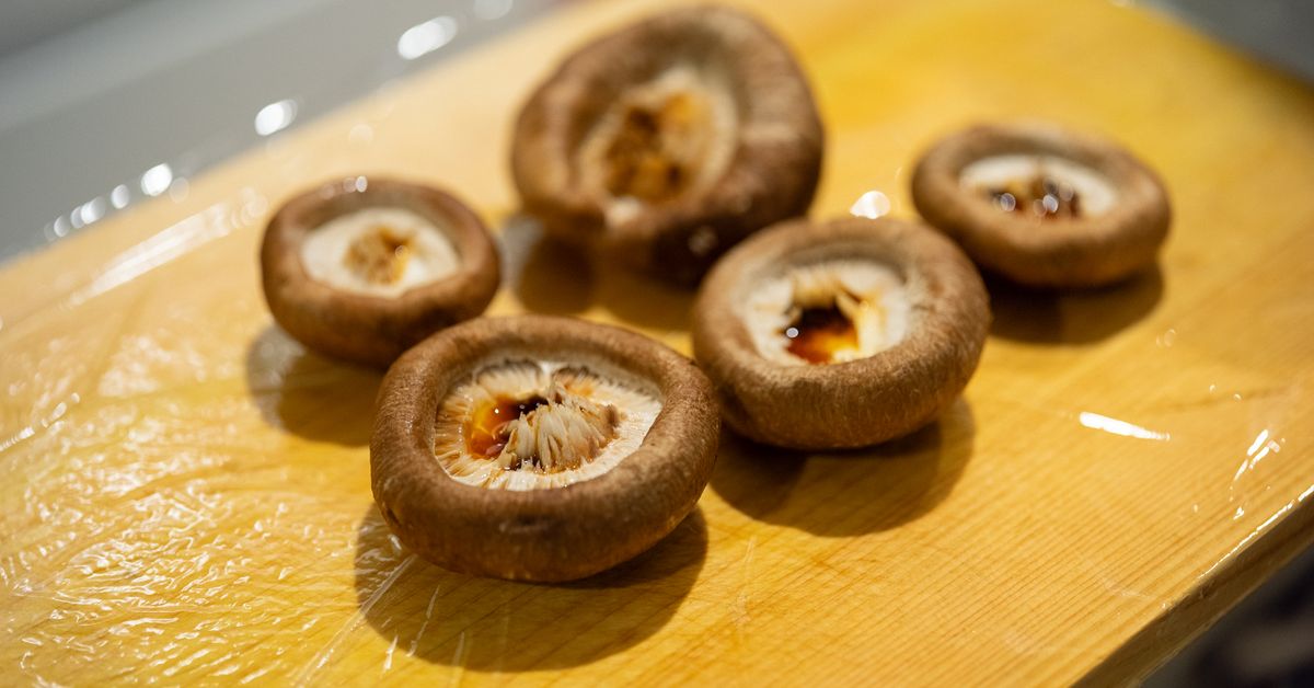 Whole shiitake mushrooms arranged on a pale cutting board