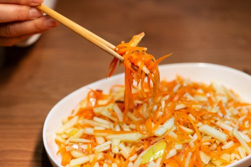 Free A vibrant carrot and apple salad served with chopsticks on a wooden table. Stock Photo