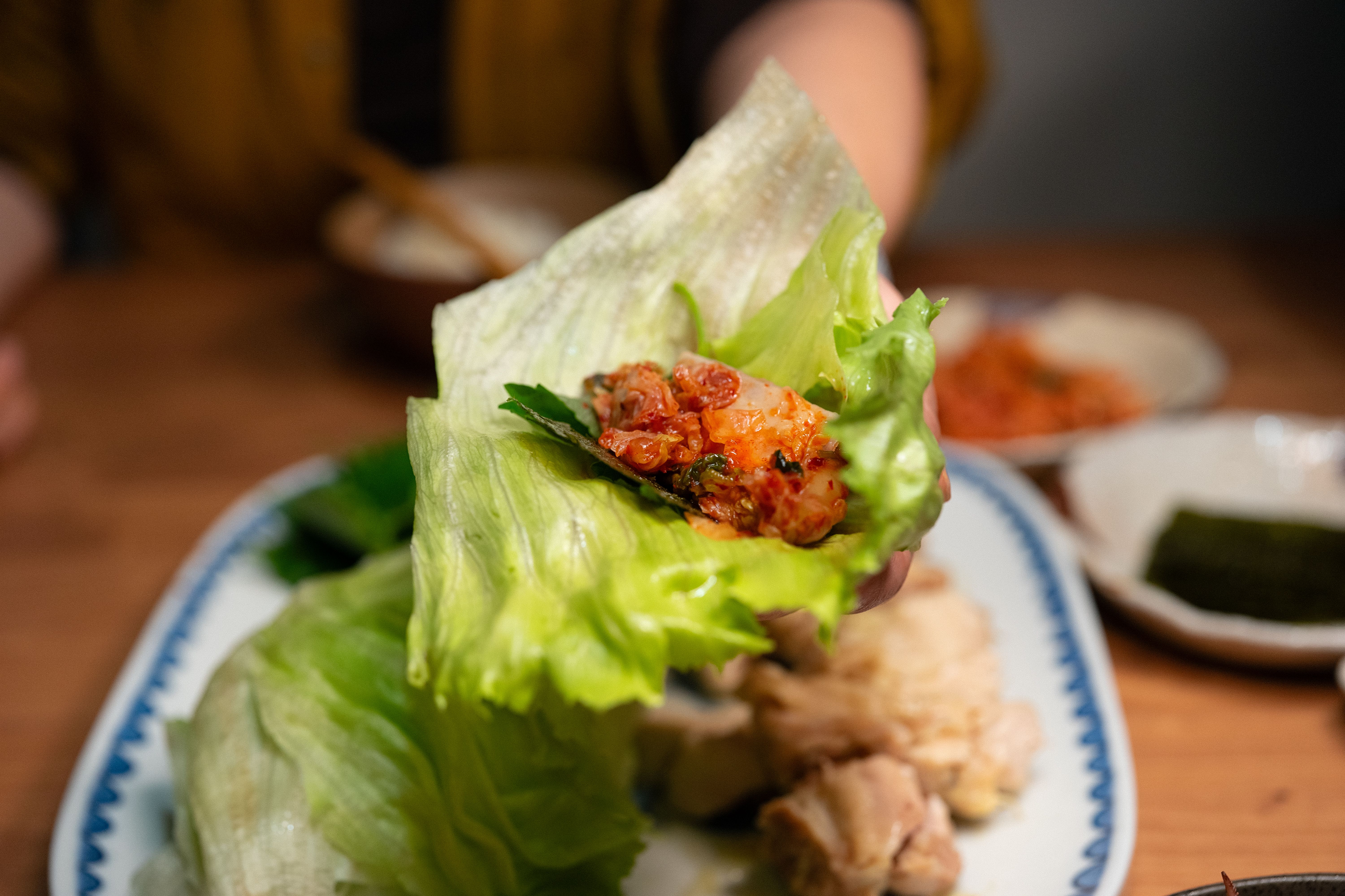 Close-up of a vibrant Korean lettuce wrap filled with spicy kimchi, highlighting fresh ingredients.