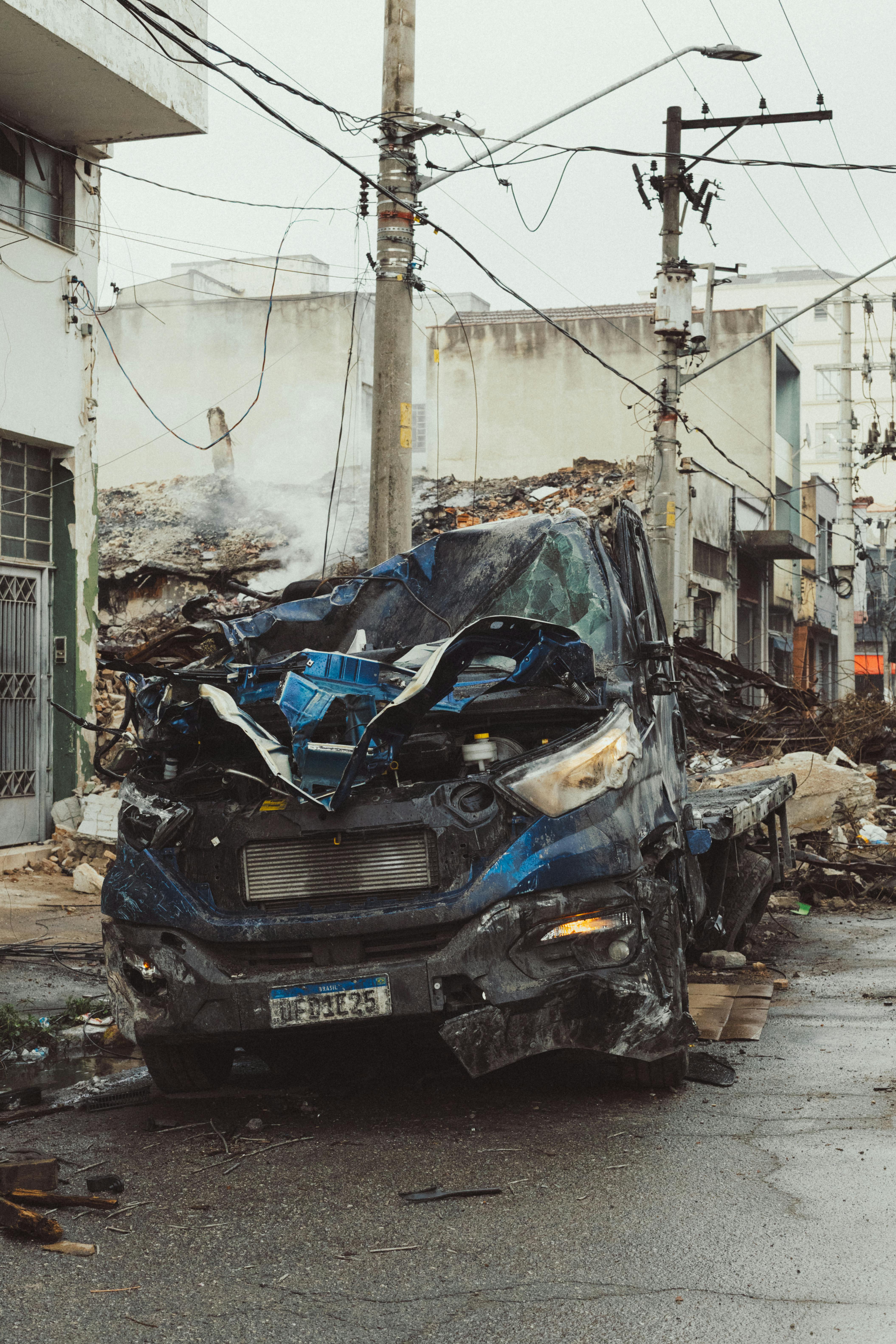 A wrecked truck amid debris on an urban street, capturing post-disaster chaos and damage.