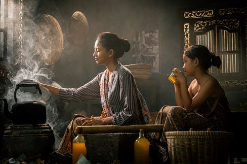 Free A mother and child in a traditional kitchen setting with warm lighting and steam. Stock Photo