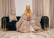 A person in Nigerian traditional attire seated in an elegantly decorated room with a rich ethnic ambiance.