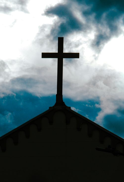 Free A dramatic silhouette of a church cross with a cloudy sky backdrop, capturing spiritual symbolism. Stock Photo