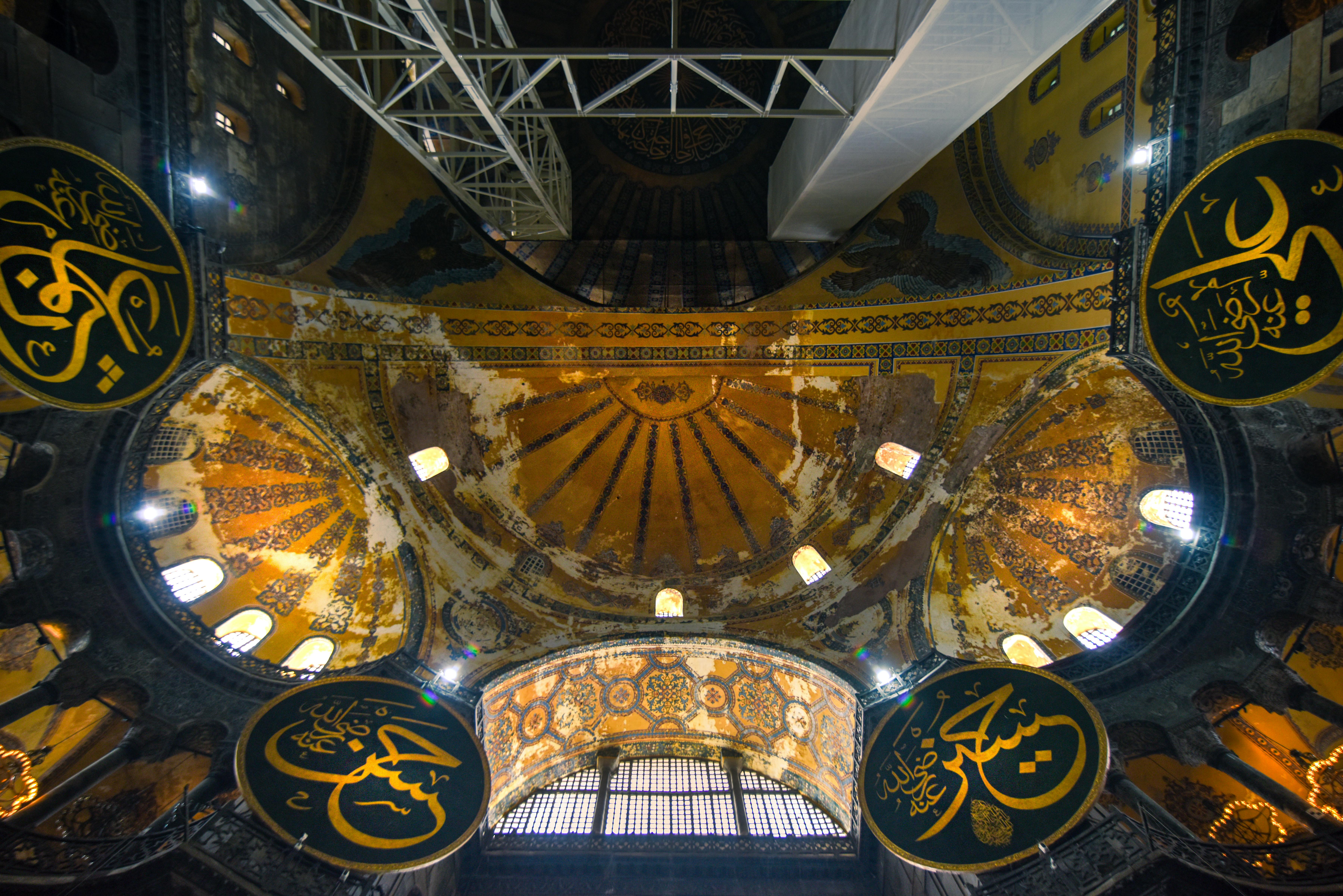 View of the ornate dome inside Hagia Sophia, showcasing detailed architecture and Arabic calligraphy