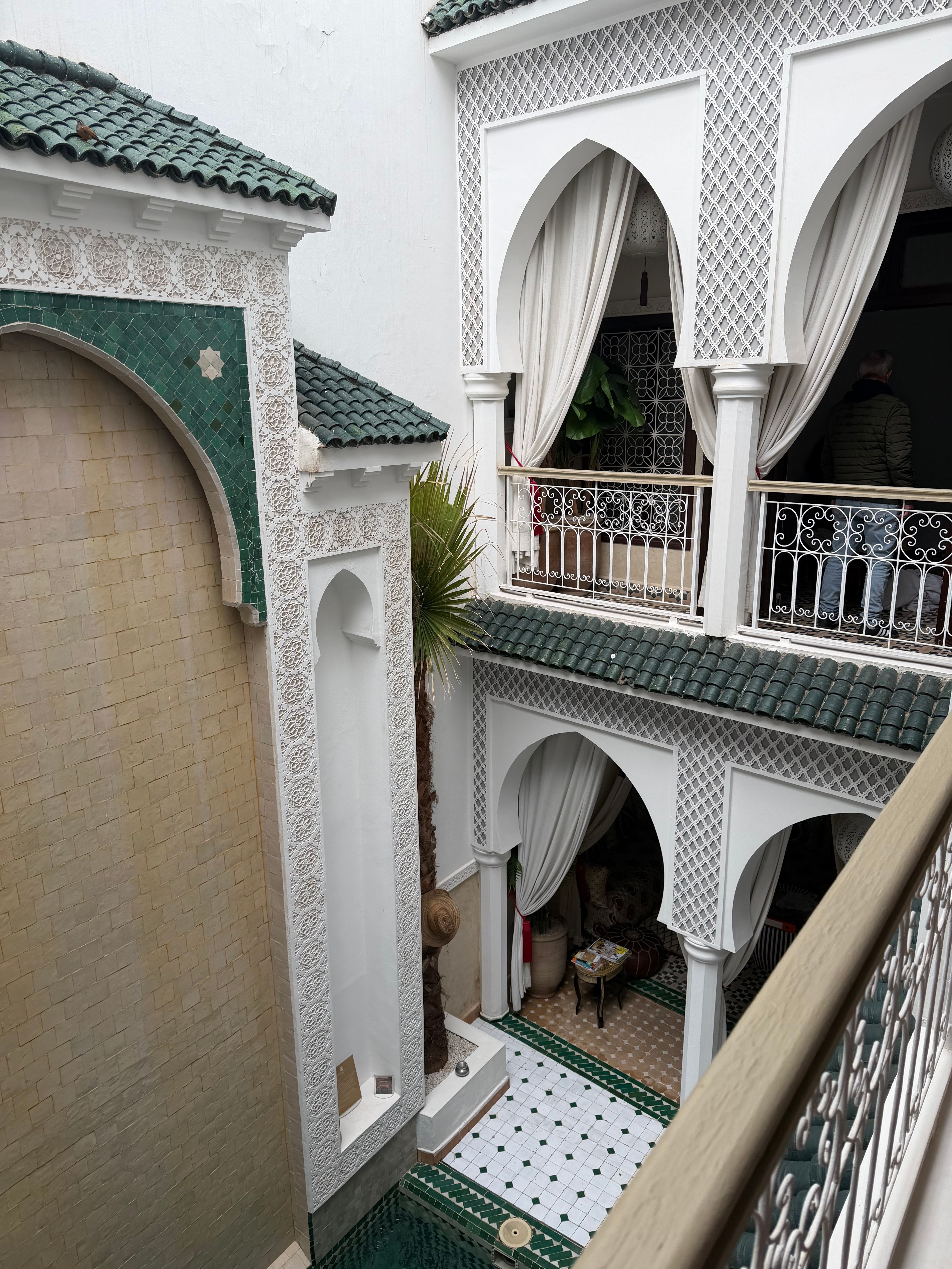 Elegant Moroccan riad interior with intricate white and green tiles in Marrakesh.