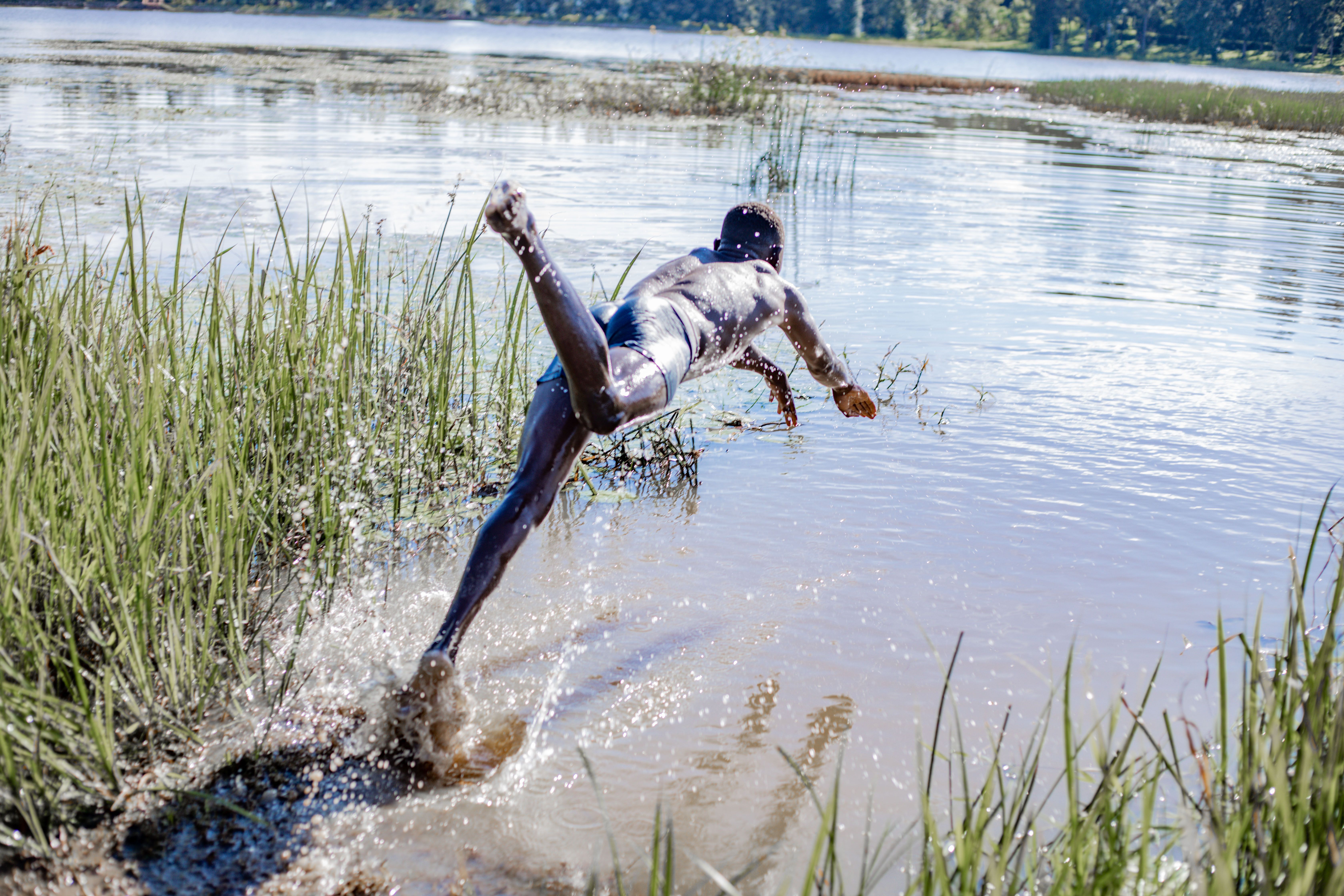 Man diving into a clear lake surrounded by nature, South Sudan