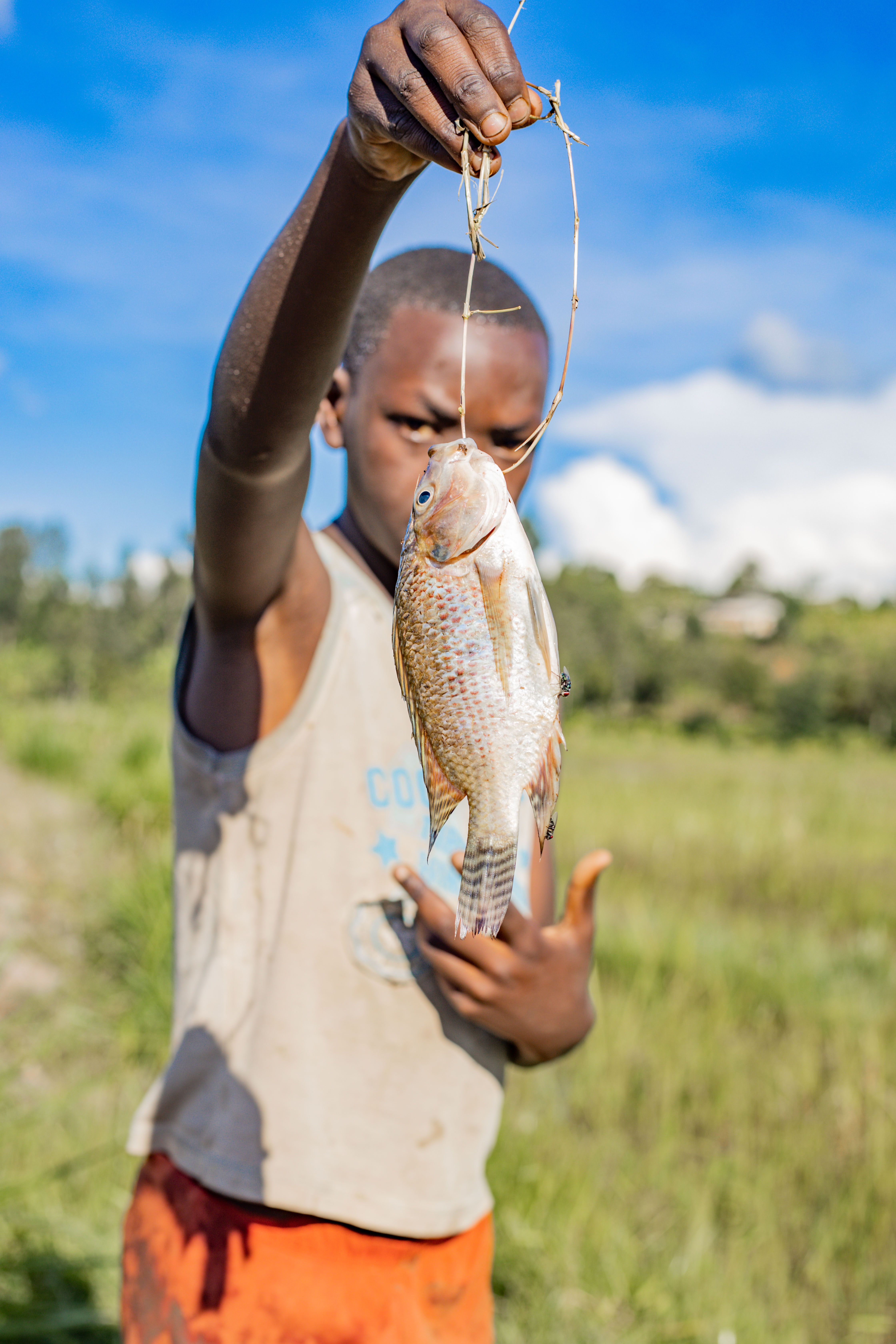 Child proudly holds a freshly caught fish outdoors, showcasing a successful fishing adventure.
