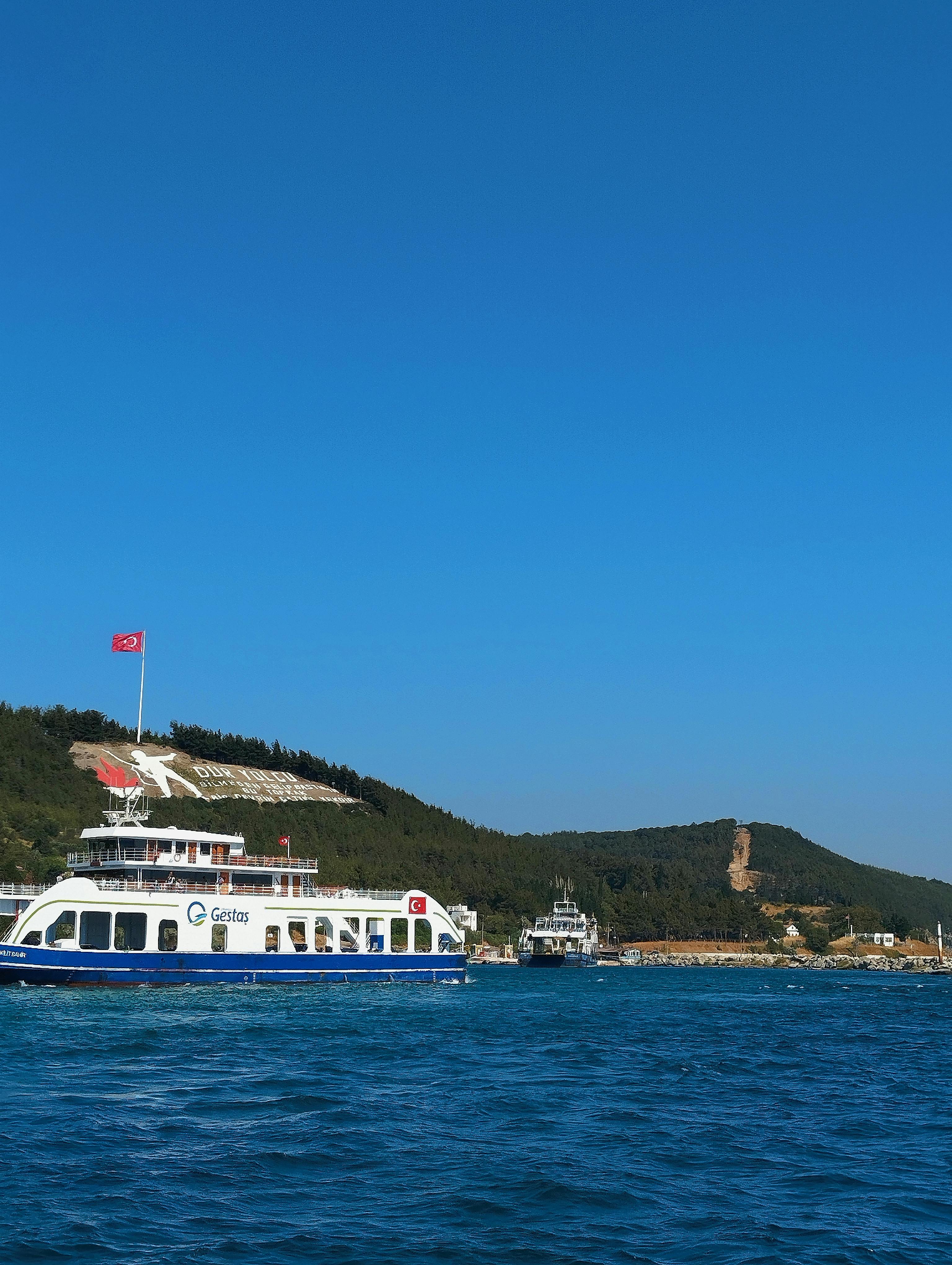 Ferry crossing blue waters with scenic coastline in the background, ideal for travel and tourism themes.